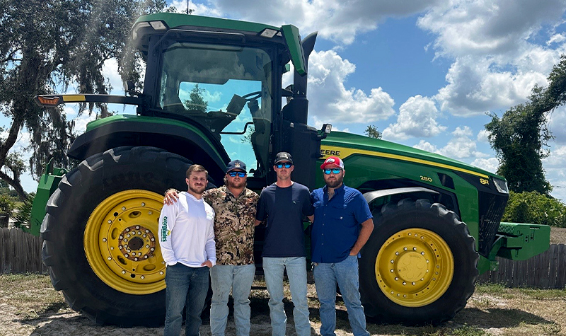 Four men standing in front of a tractor